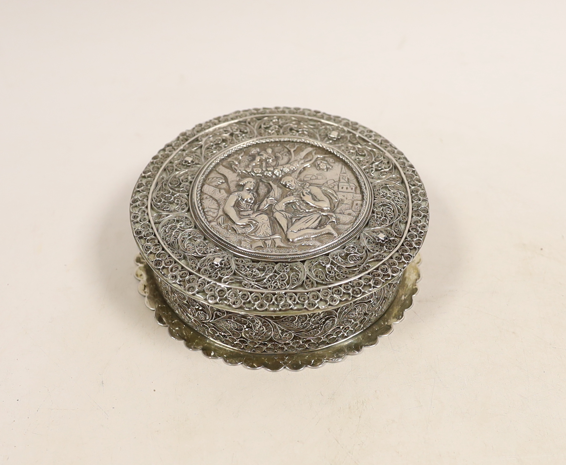 A continental white metal circular box and cover, with applied filigree decoration, diameter 11.2cm, 8.5oz.